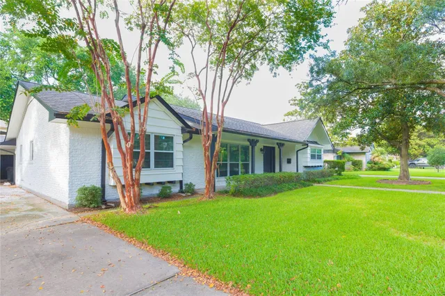 a front view of a house with a garden and trees