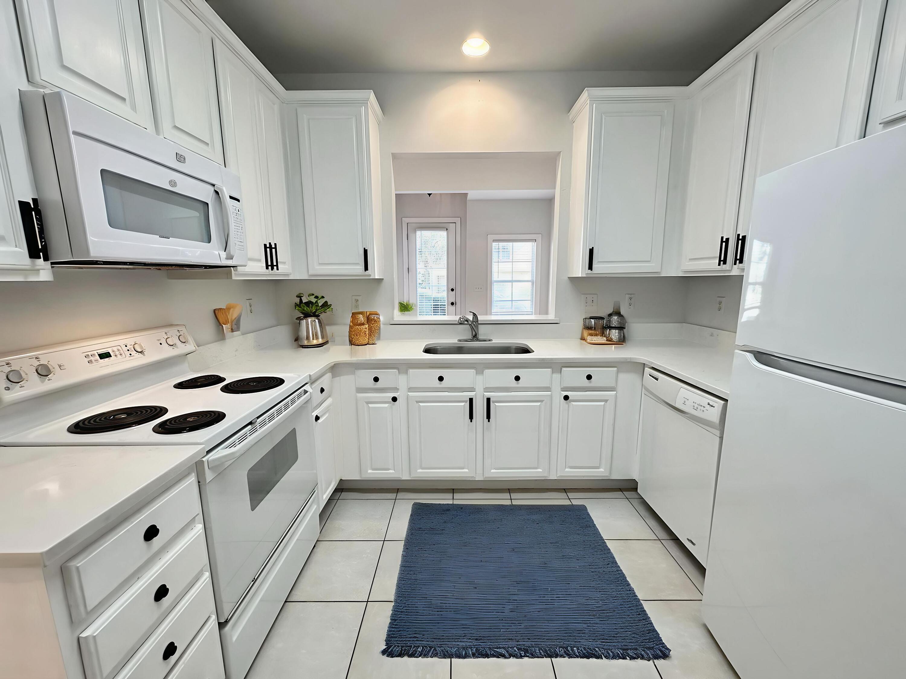 108 Mantero Way Destin, FL 32541 - Photo 16 of 36 a kitchen with white cabinets sink and white appliances