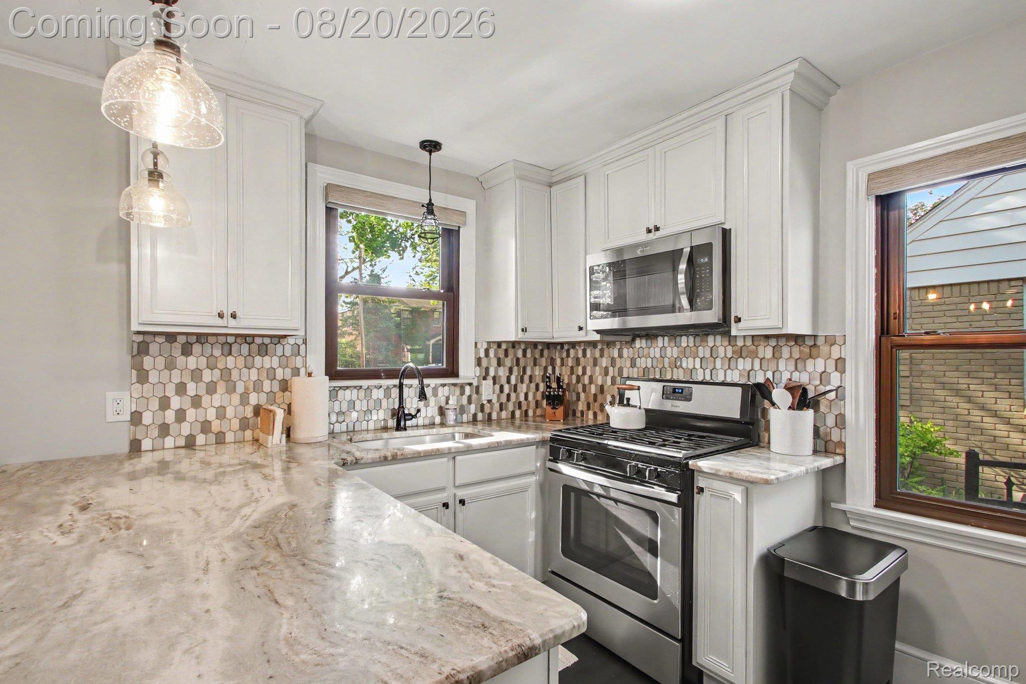 4098 Wakefield Road Berkley, MI 48072 - Photo 12 of 49 White cabinetry with crown molding, patterned tile backsplash, light-colored countertops, stainless steel appliances, and pendant lighting