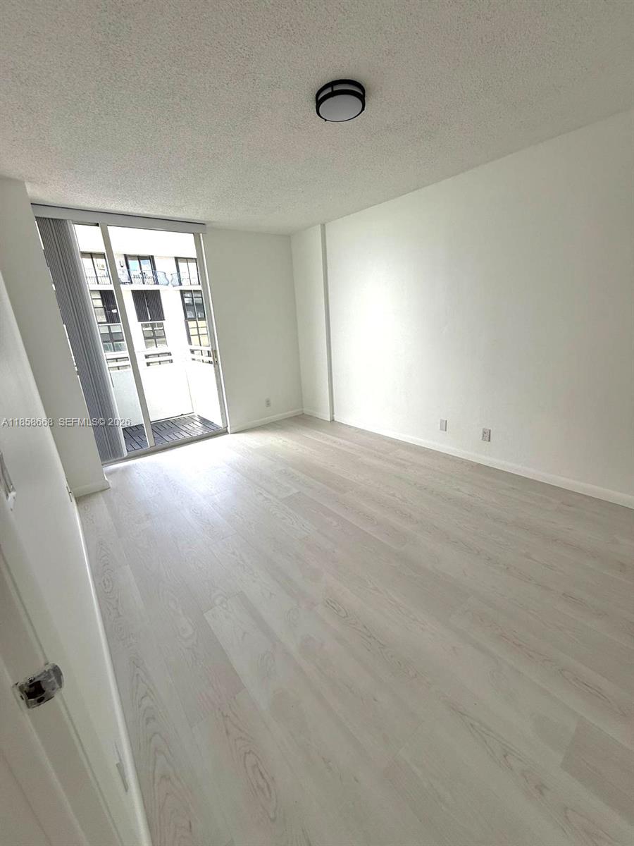 8911 Collins Avenue, Unit 1004 Surfside, FL 33154 - Photo 23 of 38 a view of an empty room with wooden floor and a window