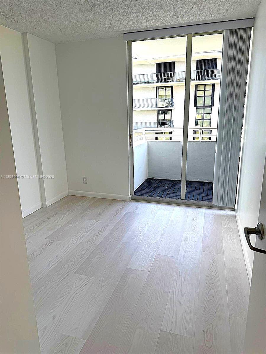 8911 Collins Avenue, Unit 1004 Surfside, FL 33154 - Photo 27 of 33 an empty room with wooden floor and windows