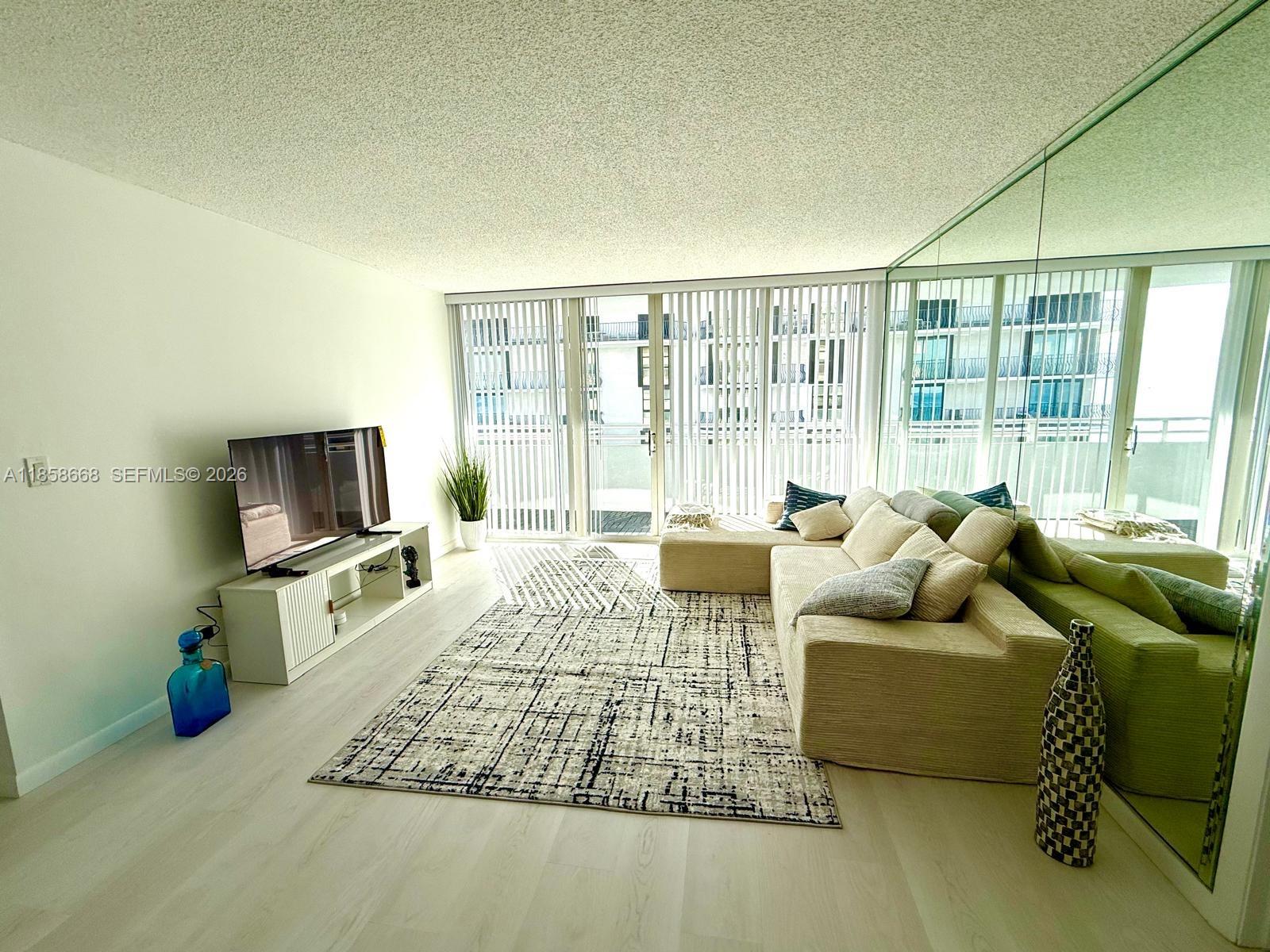 8911 Collins Avenue, Unit 1004 Surfside, FL 33154 - Photo 38 of 38 a living room with furniture and a flat screen tv