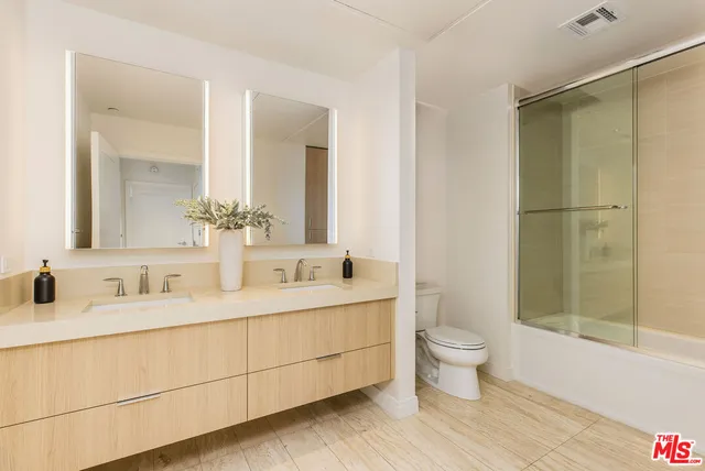a bathroom with a double vanity sink toilet mirror and shower
