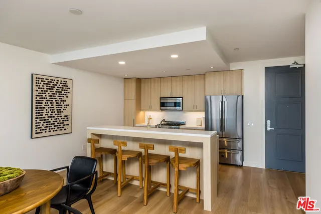 a kitchen with stainless steel appliances a refrigerator a stove a sink dishwasher with a dining table and chair