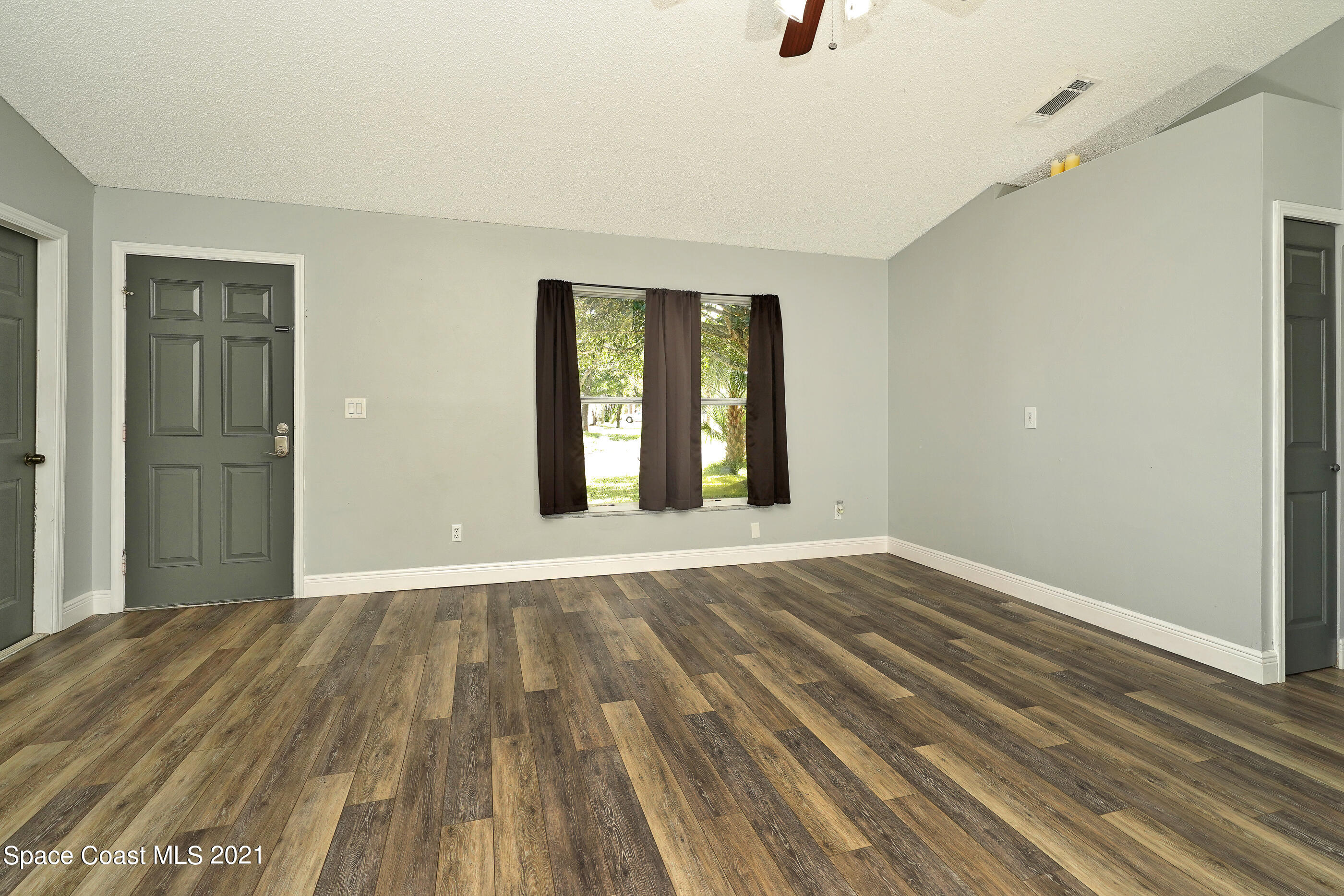 905 Macco Road Cocoa, FL 32927 - Photo 5 of 27 a view of an empty room with wooden floor and a window