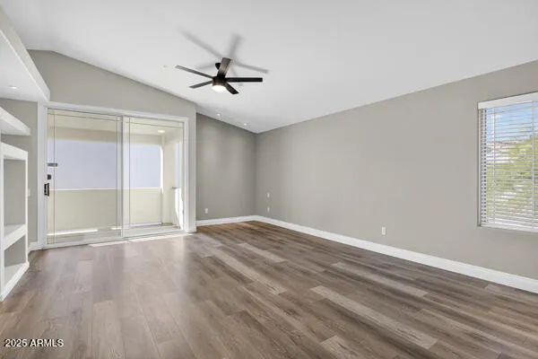 a view of an empty room with wooden floor and a window