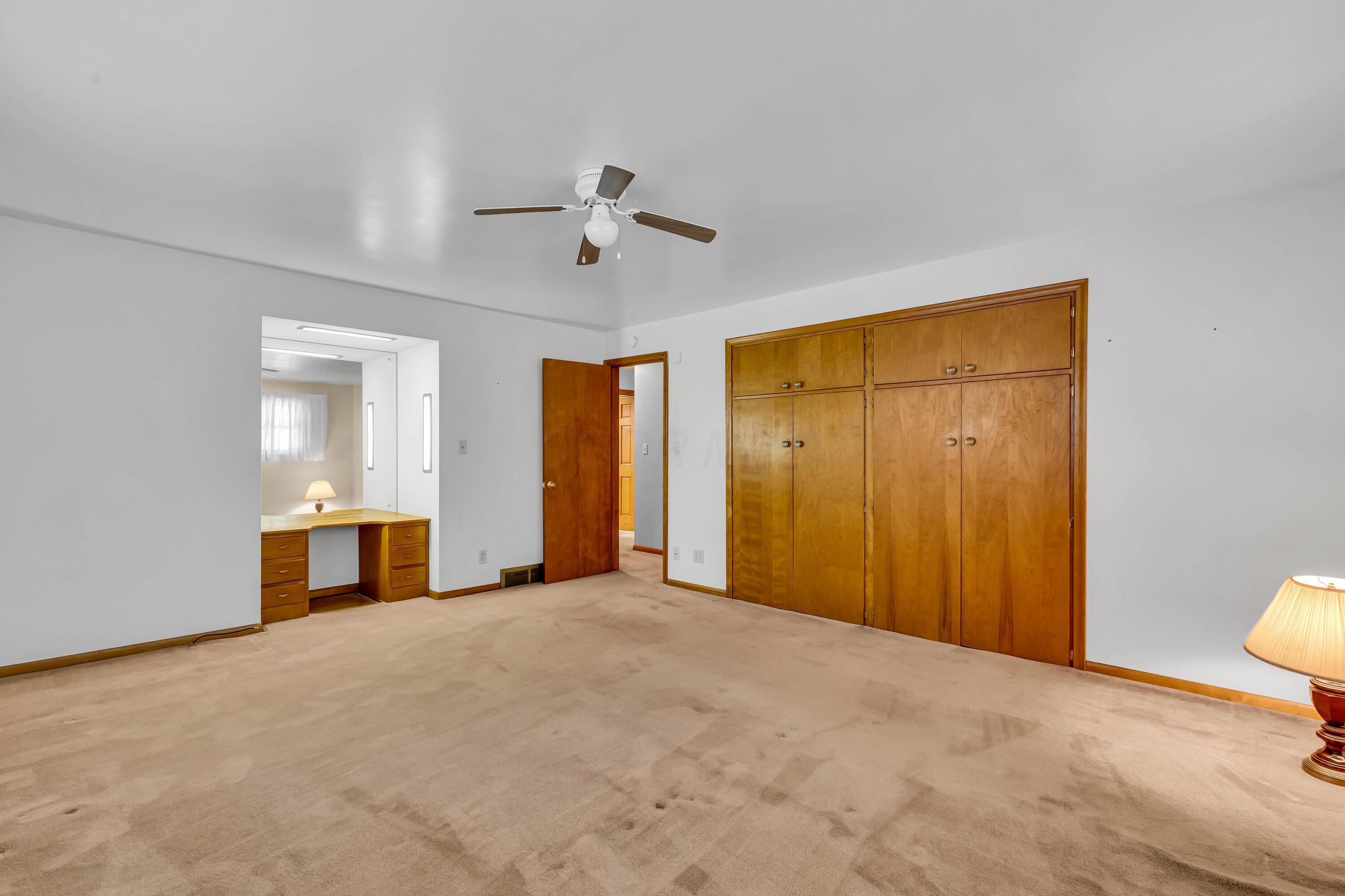 1213 East Cooke Road Columbus, OH 43224 - Photo 35 of 57 • Tan carpet • Hardwood flooring under carpet • Tan painted walls • Lighted ceiling fan • Deep, lighted closet • Built-in desk/vanity