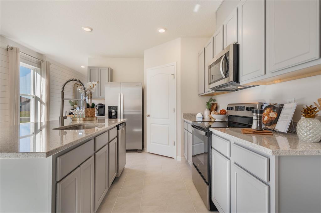 4201 Evernia Road Tavares, FL 32778 - Photo 11 of 25 a kitchen with stainless steel appliances granite countertop a stove top oven a sink a refrigerator and white cabinets