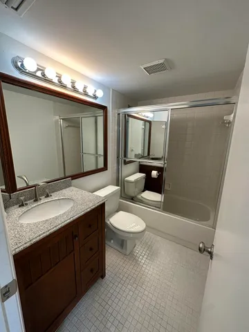 a bathroom with a granite countertop sink toilet and mirror