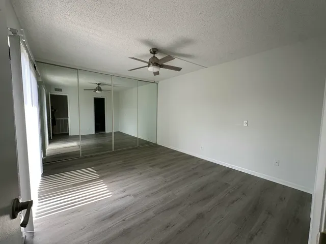 an empty room with wooden floor and fan