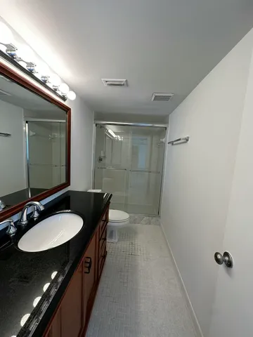 a bathroom with a granite countertop sink a mirror and a shower