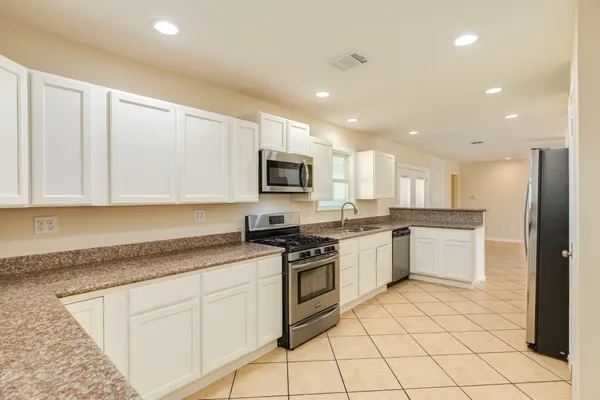 a kitchen with granite countertop white cabinets and stainless steel appliances