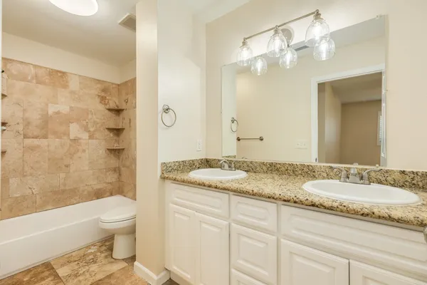 a bathroom with a granite countertop sink a toilet and shower
