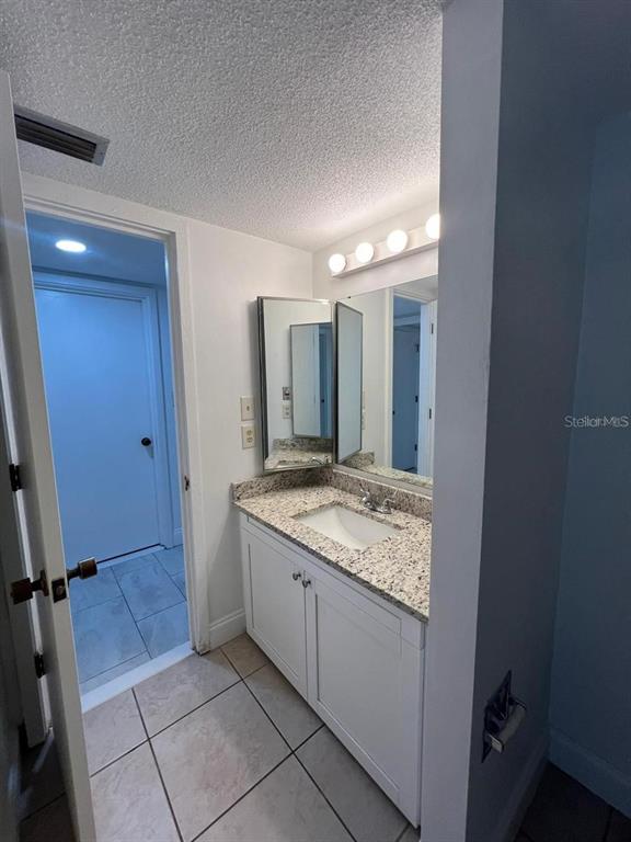 2220 Burnway Road, Unit 2220 Haines City, FL 33844 - Photo 4 of 16 a bathroom with a granite countertop sink a mirror and a shower
