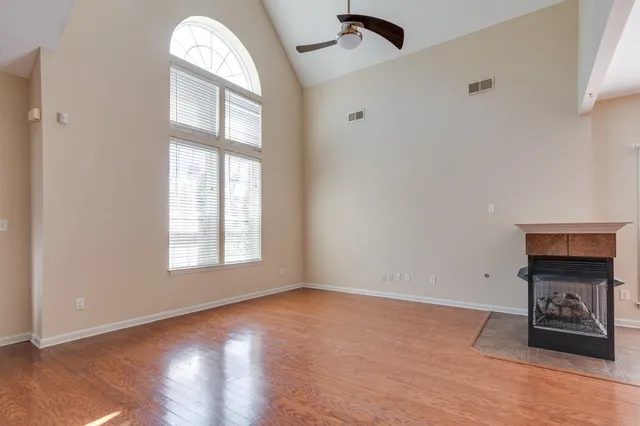 an empty room with wooden floor cabinet and windows