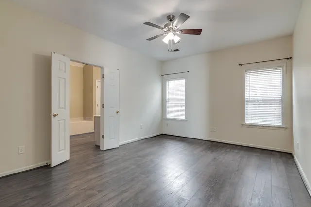 a view of an empty room with a window and wooden floor
