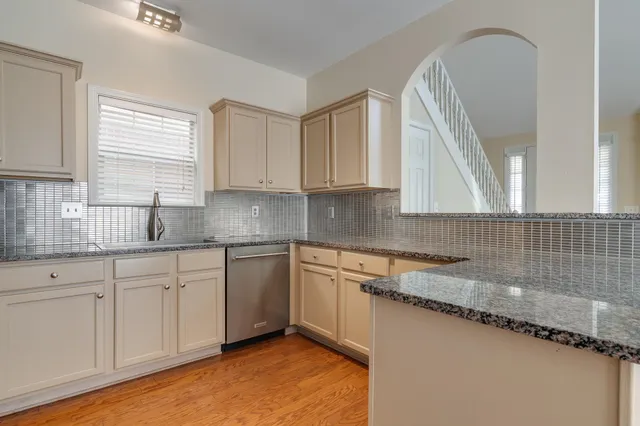 a kitchen with granite countertop a sink a window and cabinets