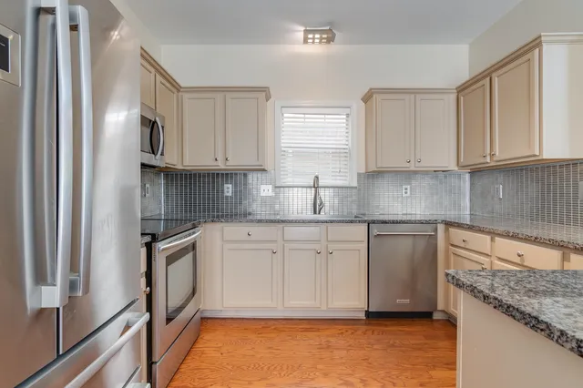 a kitchen with granite countertop stainless steel appliances a sink stove and cabinets