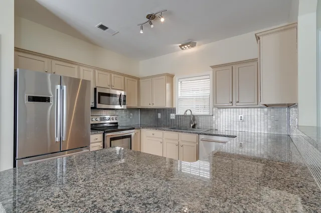 a kitchen with stainless steel appliances granite countertop a refrigerator sink and cabinets