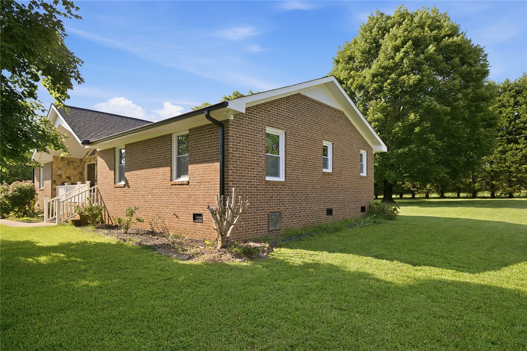 902 Cherokee Road Pelzer, SC 29669 - Photo 34 of 38 A well-maintained brick exterior residence nestled amidst mature trees and a verdant lawn.