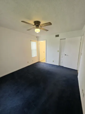 an empty room with a fan & a ceiling fan