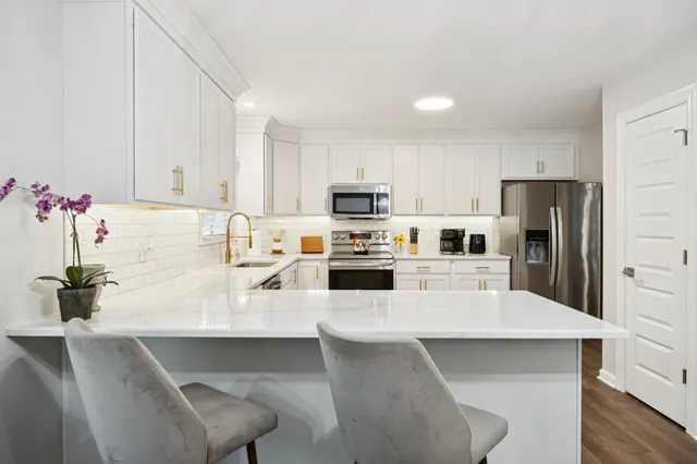 a kitchen with a sink a microwave a refrigerator and white cabinets