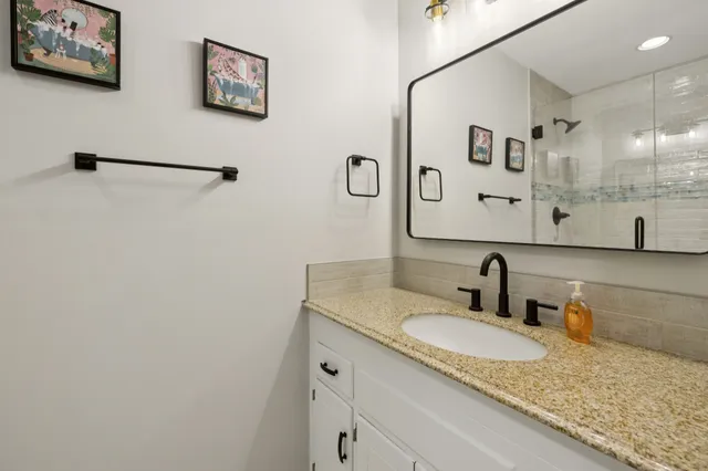 a bathroom with a granite countertop sink and a mirror