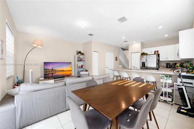 a living room with furniture a flat screen tv and kitchen view
