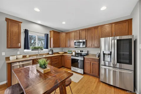 a kitchen with a refrigerator a stove a sink a dining table and chairs