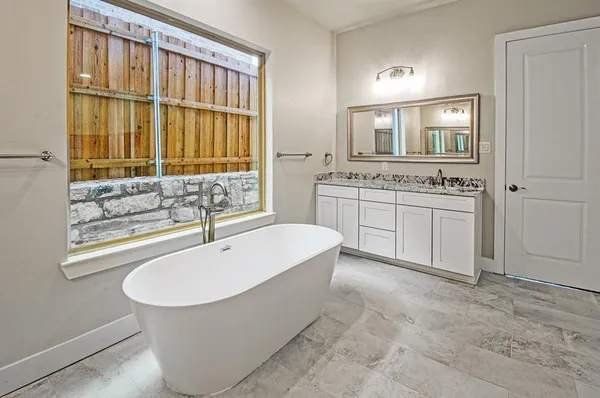 a spacious bathroom with a tub sink and mirror