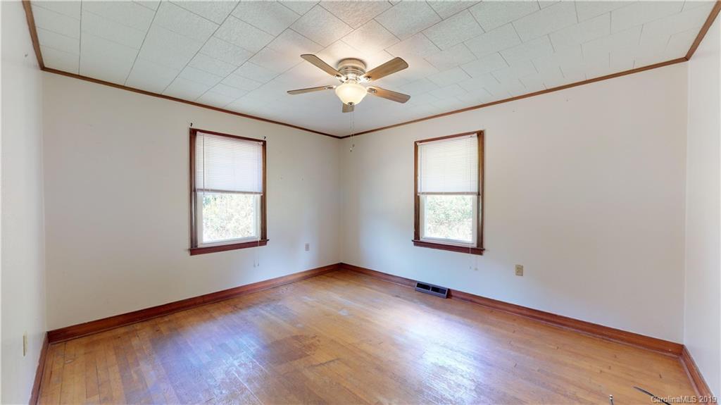 8617 Cruso Road Canton, NC 28716 - Photo 25 of 30 an empty room with wooden floor chandelier fan and windows