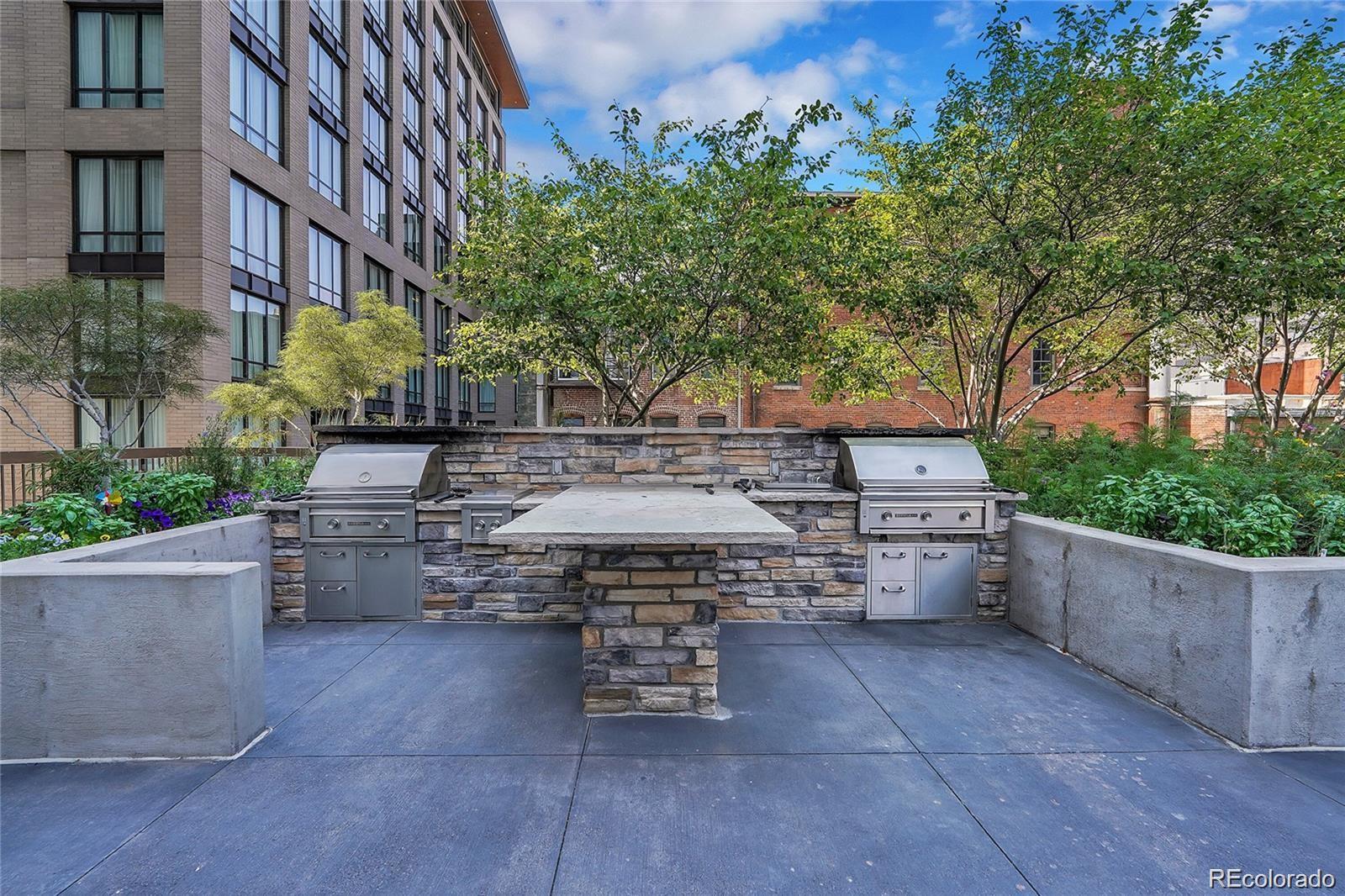 1625 Larimer Street, Unit 1007 Denver, CO 80202 - Photo 19 of 28 a view of a patio with table and chairs potted plants and large tree