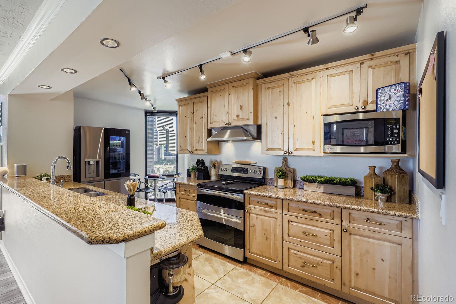 1625 Larimer Street, Unit 1007 Denver, CO 80202 - Photo 5 of 28 a kitchen with granite countertop a sink stainless steel appliances and white cabinets