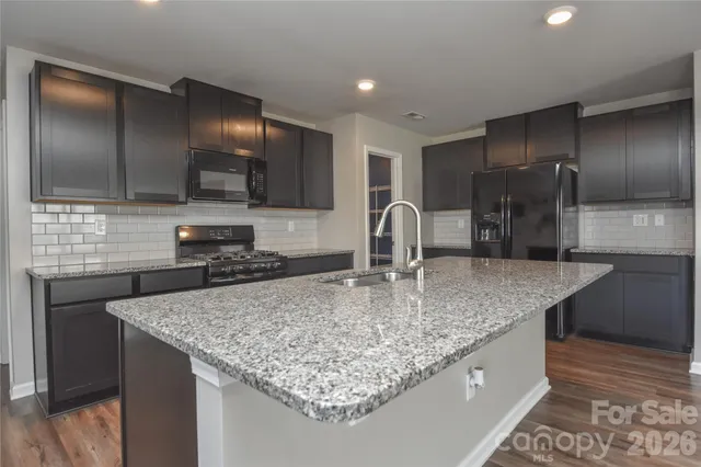 a kitchen with kitchen island granite countertop a sink and refrigerator
