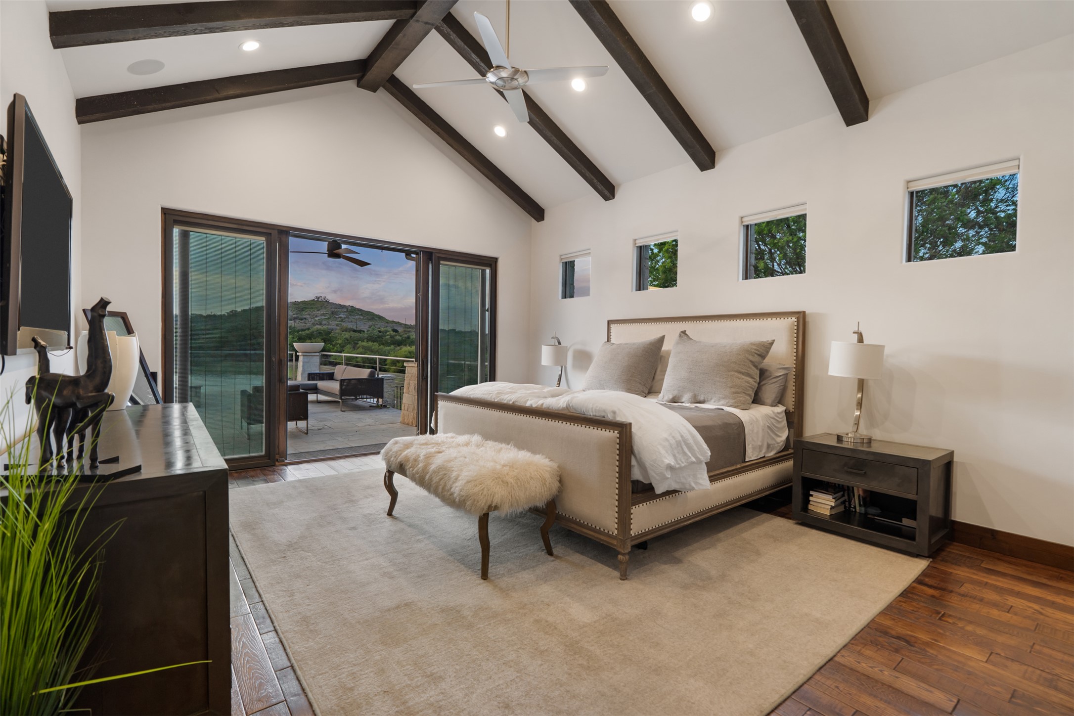 421 Rolling Hills Road Blanco, TX 78606 - Photo 13 of 40 This first of two primary bedrooms features a spacious room with vaulted ceilings and exposed wooden beams with private access to the back patio.