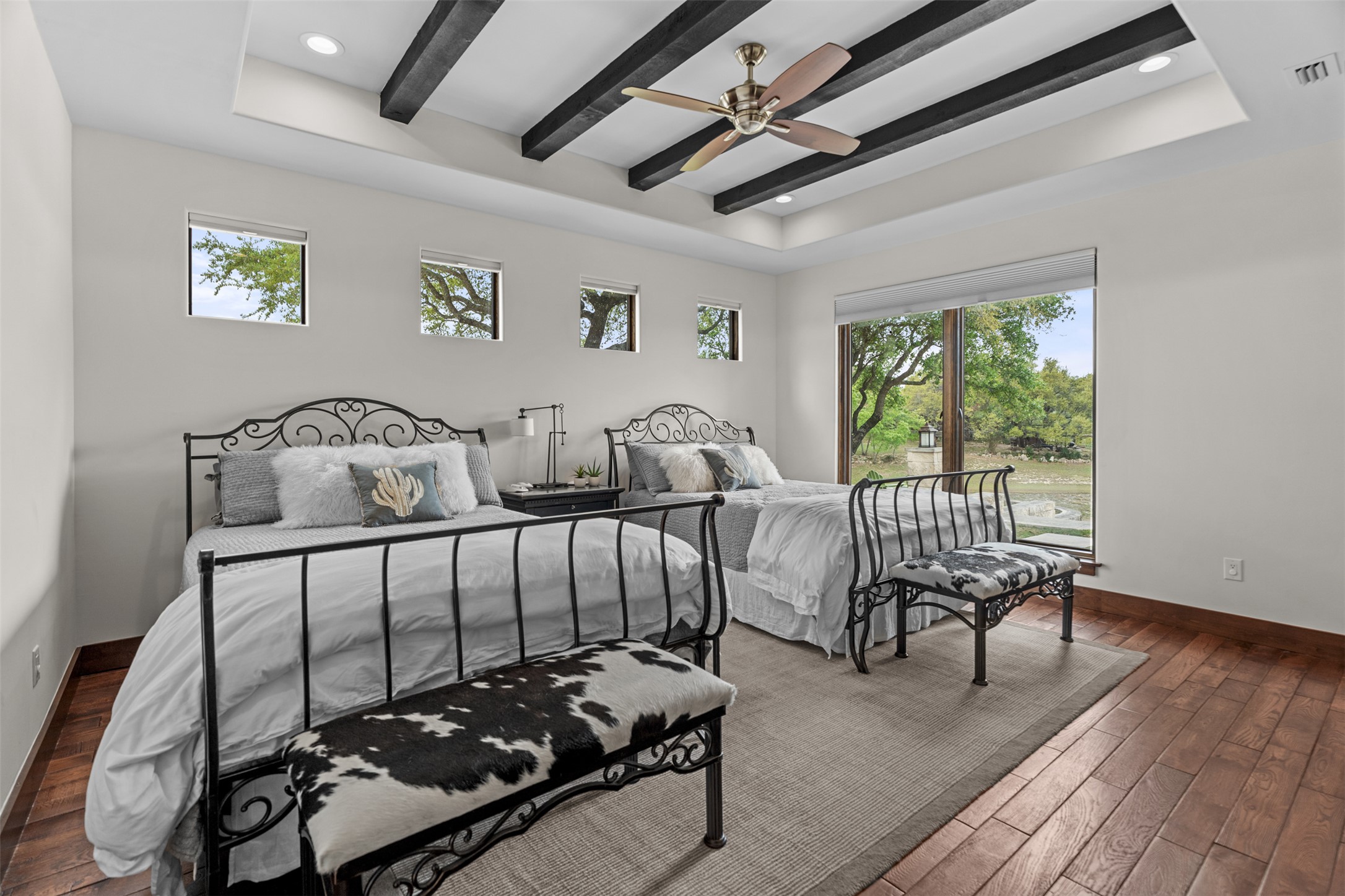 421 Rolling Hills Road Blanco, TX 78606 - Photo 16 of 40 This second primary bedroom features hardwood flooring, a tray ceiling with dark wood beams, and a fantastic view of the lake.