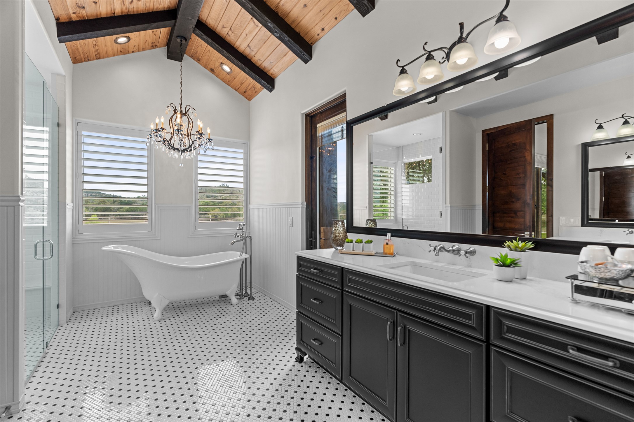 421 Rolling Hills Road Blanco, TX 78606 - Photo 18 of 40 This bathroom features a vaulted ceiling with exposed wood beams, a freestanding clawfoot tub, and a glass-enclosed shower.