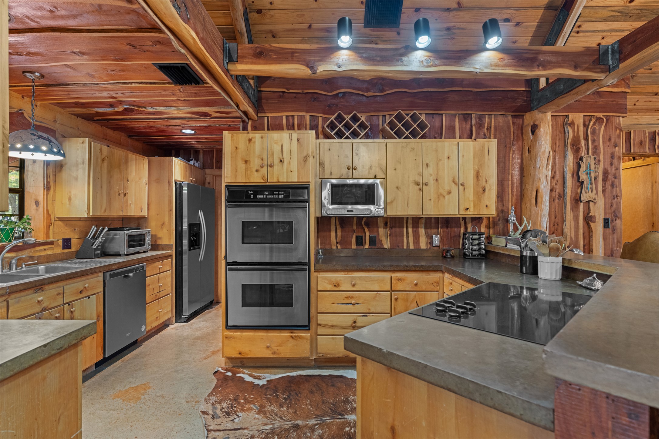 421 Rolling Hills Road Blanco, TX 78606 - Photo 23 of 40 Kitchen featuring wood cabinetry, stainless steel appliances, a built-in cooktop, and concrete countertops.