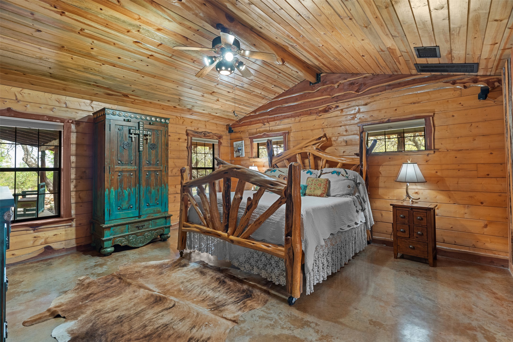 421 Rolling Hills Road Blanco, TX 78606 - Photo 24 of 40 The log-cabin's primary bedroom features extensive wood paneling on the walls and ceiling, creating a warm, natural aesthetic.