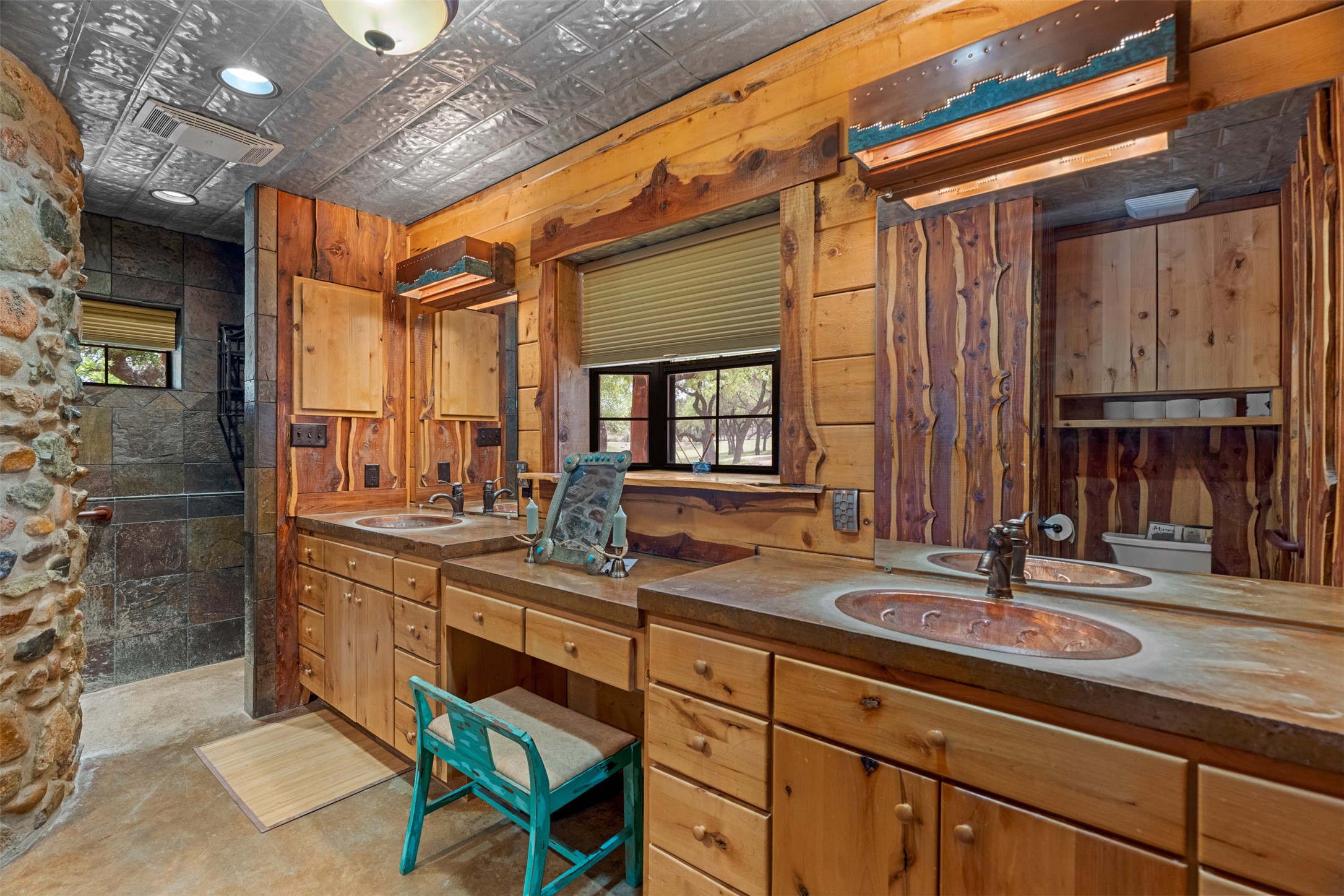 421 Rolling Hills Road Blanco, TX 78606 - Photo 25 of 40 The bathroom features natural wood cabinetry and wall paneling, a stone shower surround, and a pressed tin ceiling.