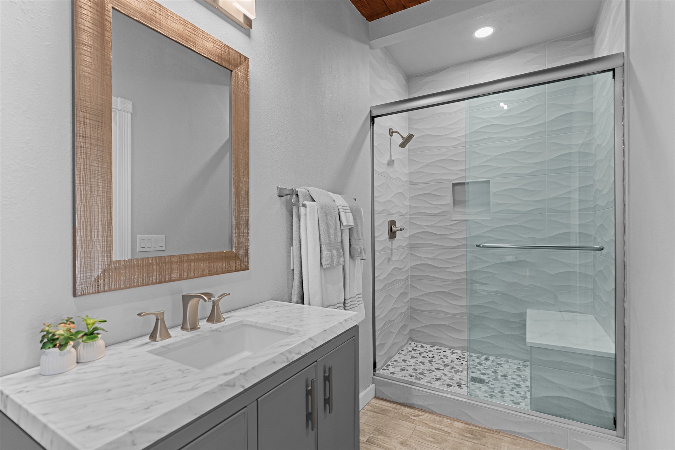 421 Rolling Hills Road Blanco, TX 78606 - Photo 33 of 40 Bathroom featuring a vanity with a white marble countertop, a large framed mirror, and a walk-in shower with a glass enclosure and a built-in bench.