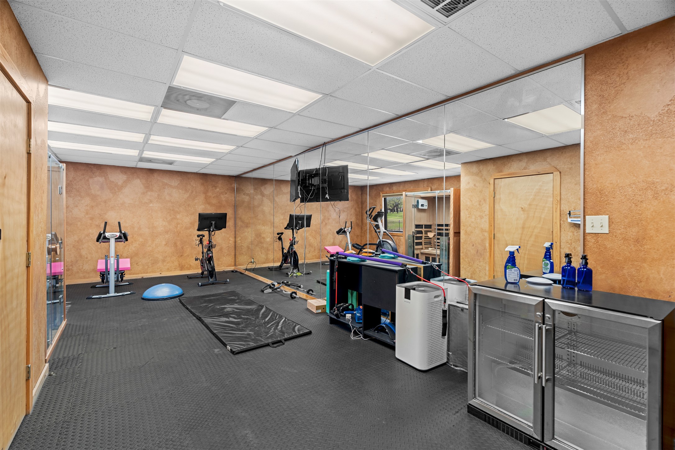 421 Rolling Hills Road Blanco, TX 78606 - Photo 38 of 40 The property features a dedicated fitness room with rubber flooring, a mirrored wall, and recessed lighting