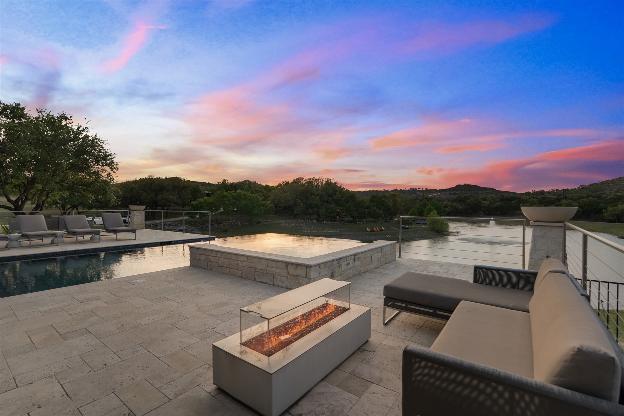 421 Rolling Hills Road Blanco, TX 78606 - Photo 7 of 40 The property features an outdoor patio with stone paving, an Infiniti pool, and a built-in fire pit.
