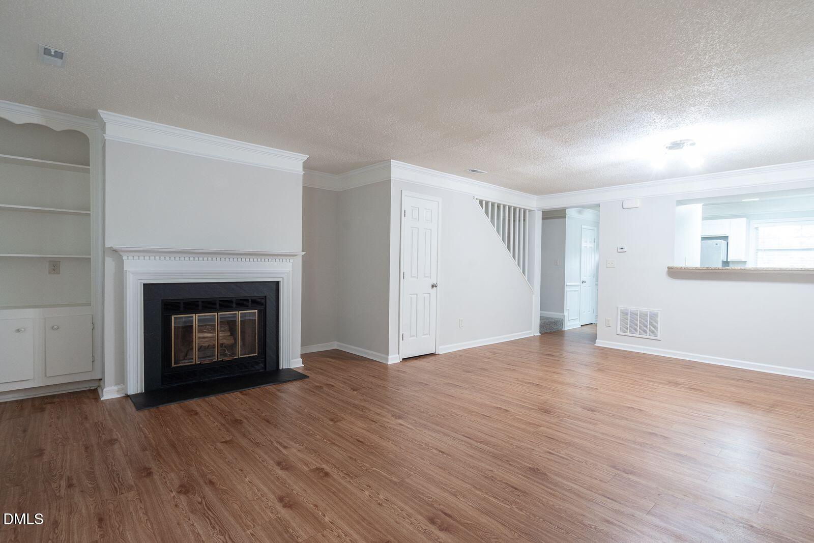 4418 Roller Court Raleigh, NC 27604 - Photo 2 of 13 a view of an empty room with wooden floor fireplace and a window