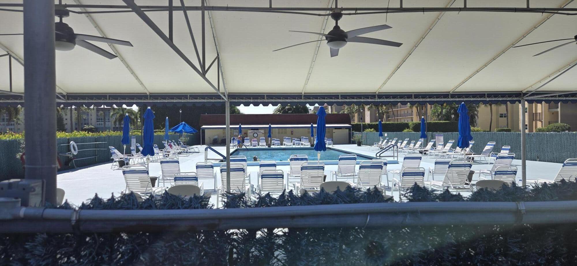 3661 Via Poinciana, Unit 306 Lake Worth, FL 33467 - Photo 13 of 13 a view of a swimming pool with a table and chairs