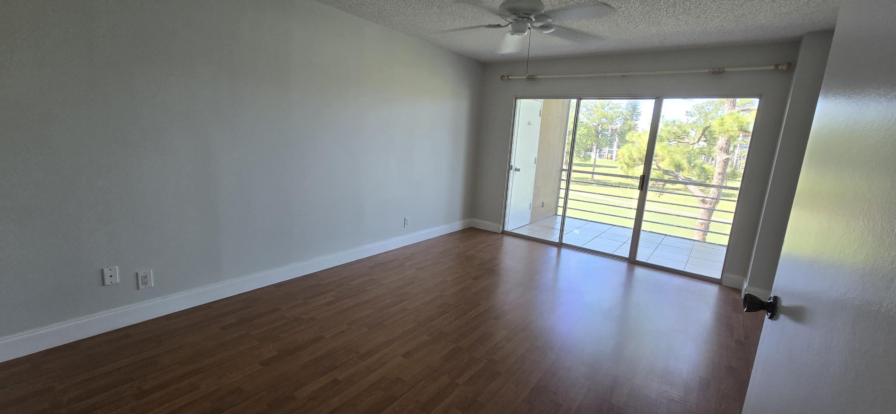 3661 Via Poinciana, Unit 306 Lake Worth, FL 33467 - Photo 4 of 13 a view of an empty room with wooden floor and a window