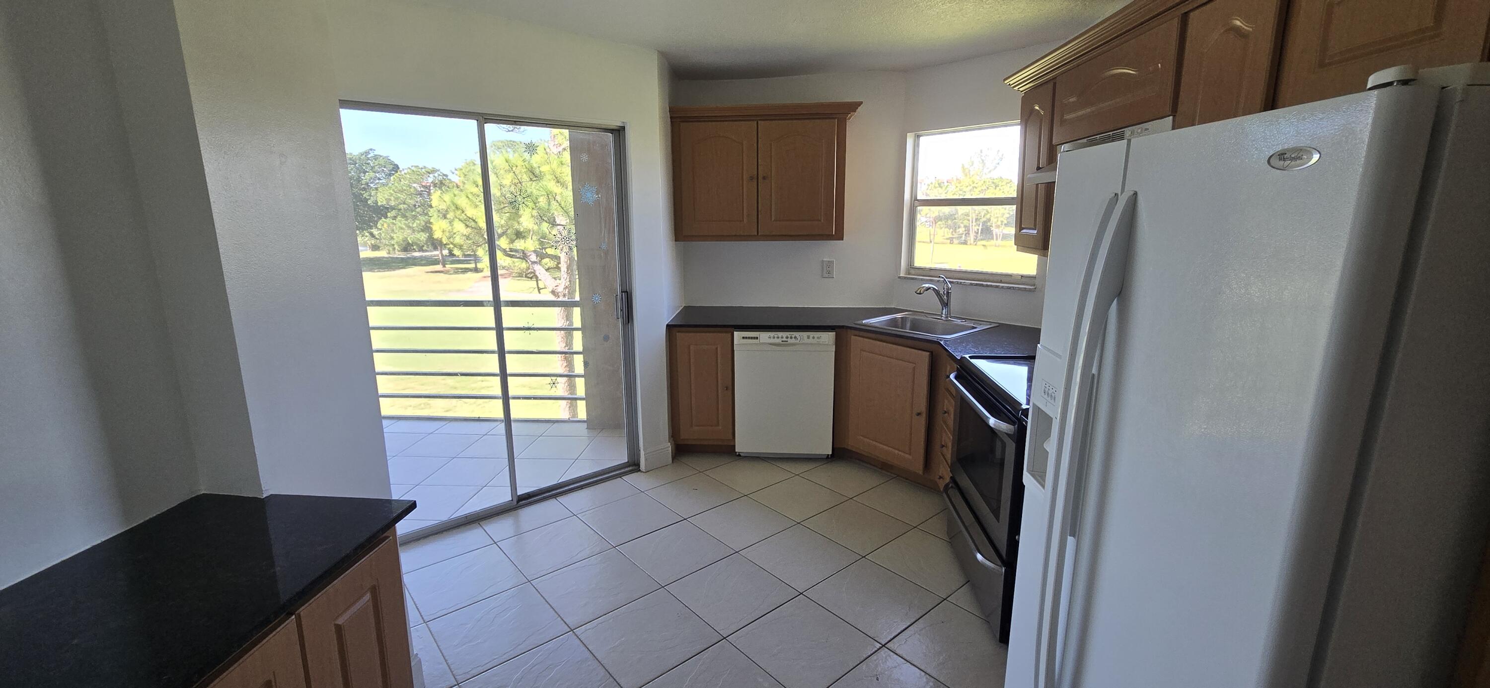 3661 Via Poinciana, Unit 306 Lake Worth, FL 33467 - Photo 5 of 13 a kitchen with stainless steel appliances a refrigerator sink and window