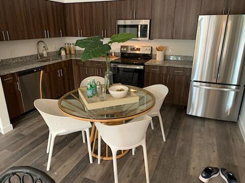 4290 Lakewood Road, Unit 101 Lake Worth, FL 33461 - Photo 2 of 13 a kitchen with granite countertop a dining table chairs stove and refrigerator