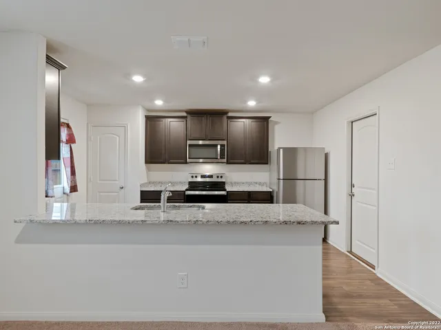 a large kitchen with stainless steel appliances kitchen island granite countertop a refrigerator a stove and a sink