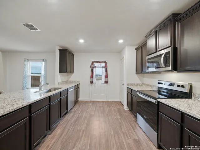 a large kitchen with stainless steel appliances granite countertop a stove a sink dishwasher and a refrigerator